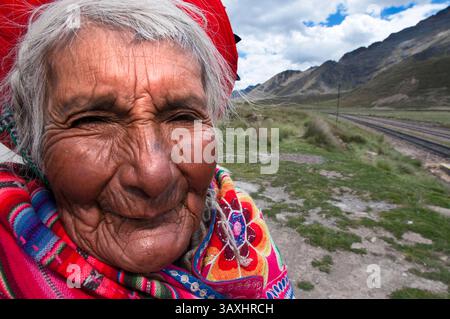 Oktober 2016 - Peru - Anden Explorer, Luxuszug von Cusco nach Puno. Eine alte Frau in traditioneller Kleidung in La Raya, die mit dem höchsten Punkt des Weges, 4313 Meter, zusammenfällt. Der Anden-Explorer-Zug Orient Express fährt zwischen Cuzco und Puno. Altiplano ist ein Hochplateau, das sich über den südlichen Anden erhebt, dem längsten Gebirgszug der Welt. Es handelt sich um eine mit Sedimenten gefüllte Vertiefung zwischen den östlichen und westlichen Ketten der Anden. Diese Füllung ereignete sich vor Millionen von Jahren, als ein alter Meeresboden hochgeschoben wurde, als die modernen Gipfel angehoben wurden. Erosionsbedingte Ablagerung Co Stockfoto
