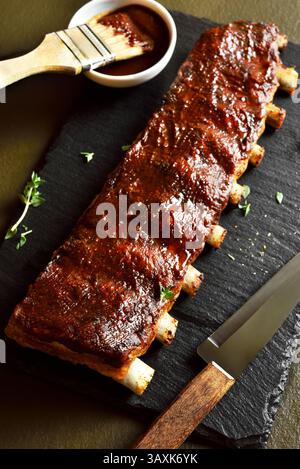 BBQ Spare Ribs auf Schieferbrett auf dunklem Hintergrund. Nahansicht Stockfoto