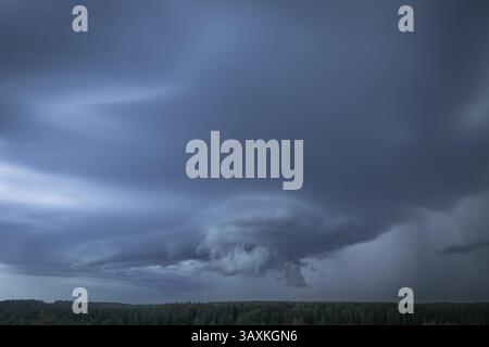 Ein dramatischer Blick auf Sturmwolken, die sich über einem riesigen grünen Wald bilden und verdunkeln. Die wirbelnde Masse der schweren Regenwolken signalisiert ein Herannahen Stockfoto