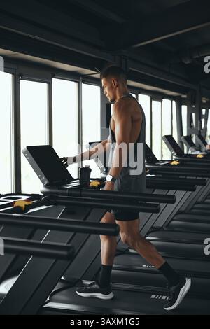 Vertikale Aufnahme eines jungen, gutaussehenden Mannes, der auf einer Laufbahn läuft, an Gesundheit und Fitness arbeitet. Stockfoto