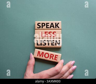 Weniger sagen, mehr hören. Holzblöcke mit Wörtern sprechen weniger Hören Sie mehr. Wunderschöner graugrüner Hintergrund. Geschäftsmann Hand. Geschäftlich und sprich Stockfoto