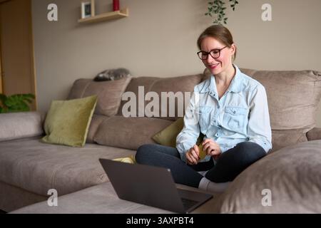 Frau, die zu Hause online einkaufen geht auf Laptop mit Kreditkarte Stockfoto