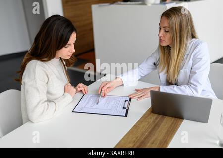 Hochwinkelansicht einer Ärztin, die Ergebnisse medizinischer Tests mit Patienten am Schreibtisch in der Klinik zeigt und bespricht Stockfoto