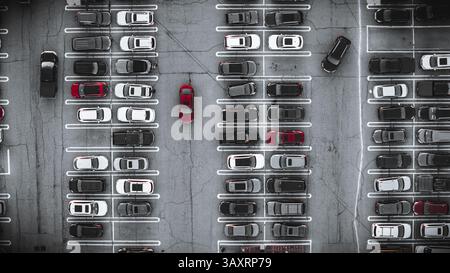 Aus der Vogelperspektive auf einen gut organisierten Parkplatz voller Autos, der Symmetrie, Kontrast und urbanes Design aus einer Top-down-Perspektive zeigt. Stockfoto