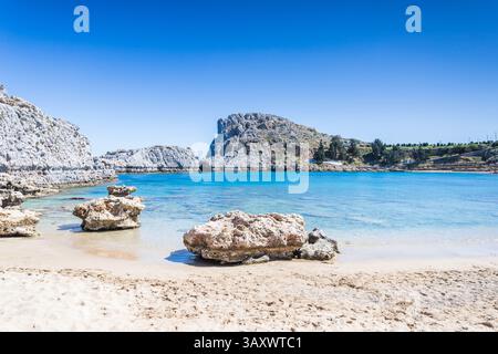 Wellen schlagen sanft gegen den goldenen Sand des Mikros Gialos Strandes in Rhodos, Griechenland. Stockfoto