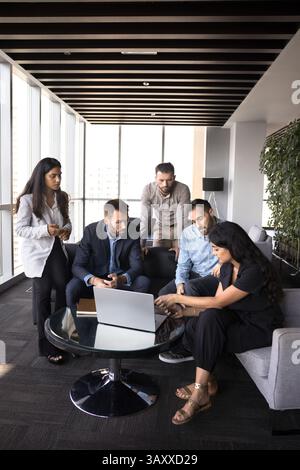 Eine Gruppe von fünf Fachleuten versammelte sich in einem modernen Büro um ein Notebook Stockfoto