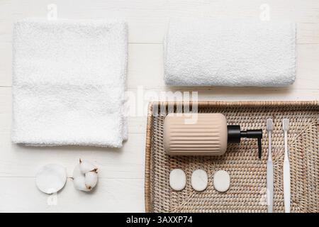 Schöne Komposition mit Korb, sauberen weichen Handtüchern und Zahnbürsten auf weißem Holzhintergrund Stockfoto