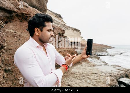 Ein Mann unterhält sich während seines Urlaubs durch einen Videoanruf am Strand. Stockfoto