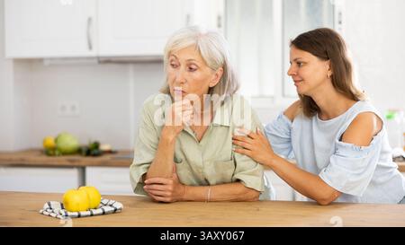 Eine Frau tröstet ihre depressive ältere Mutter Stockfoto