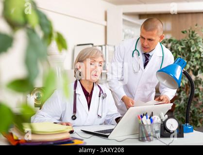 Ältere Ärztin im Büro mit männlichen Kollegen Stockfoto
