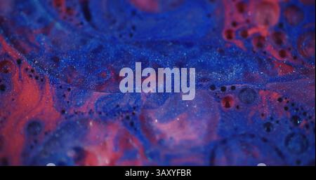Glitzertinte. Unfokussierter Flüssigkeitsfluss. Schöne blaue rote Farbe flüssige Farbe transparente Blasen Bewegung auf verschwommenem Bokeh hellen modernen Hintergrund. Stockfoto