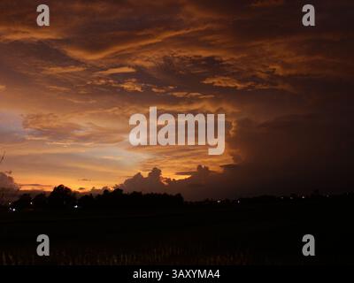 Golden Hour Sky mit dramatischen Wolken über Silhouetten der ländlichen Landschaft in der Abenddämmerung in Indonesien Stockfoto