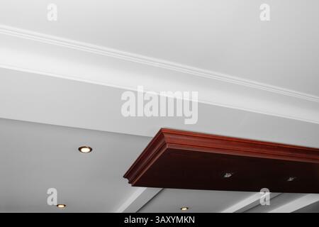 Abgehängte und Gitterdecke mit LED-Spots und Trockenbaukonstruktion in leerem Raum im Innenraum des Hauses. Stretchdecke weiß und komplexe Form. Stockfoto