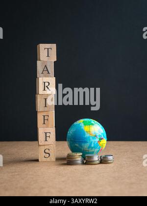 Zölle, Wort auf gestapelten quadratischen Holzblöcken. Neben Miniaturkugel und Münzen. Stockfoto