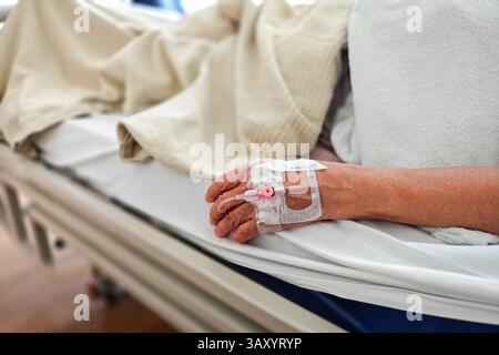 Patient im Krankenhausbett liegend. Nahaufnahme der Hand mit Infusionslösung. Stockfoto