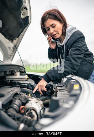 Fahrerin mit kaputtem Auto auf der Straße spricht am Telefon mit Service Stockfoto