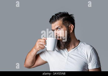 Guten Morgen, Mann mit einer Tasse Tee. Gutaussehender bärtiger Mann hält eine Tasse Kaffee, Tee. Hipster-Mann mit einer Tasse frischen Kaffee. Nahaufnahme Porträt von A Stockfoto