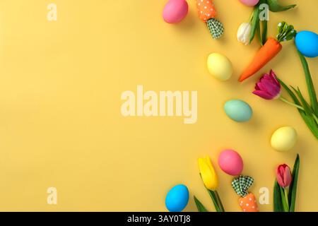 Flach lagen bunte Ostereier und Frühlingsblumen auf gelbem Hintergrund. Stockfoto