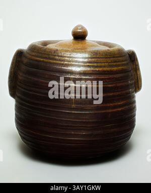 Ein runder, strukturierter Topf mit einem glatten, abgerundeten Deckel und zwei griffähnlichen Vorsprüngen, der einen warmen, erdigen Ton zeigt, der seine handgefertigte Handwerkskunst unterstreicht., Unknown (Japanisch), Wasserbehälter, 19. Jahrhundert (?), Ton, Glasur, 8 1/4 x 8 1/4 x 8 3/4 Zoll (21,0 x 21,0 x 22,2 cm), klassische Kunst mit modernem Touch, neu interpretiert von Artotop Stockfoto