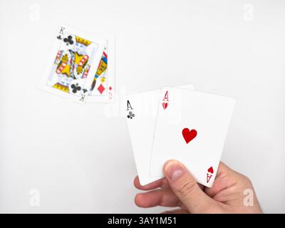 Weiße männliche Hand mit weißen Pokerkarten aus Kunststoff mit zwei Assen in der Mitte auf einem weißen Hintergrundbild. Hochwertige Fotos Stockfoto