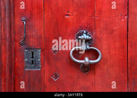 Rote Vintage-Holztür mit dekorativem Metallklopfer, Griff und Schlüssellöchern, Troyes, Frankreich Stockfoto