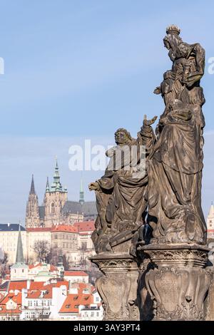 Skulpturen der historischen Figuren stehen an prominenter Stelle mit der berühmten Prager Burg, die sich in der Ferne ausbreitet und unter klarem Himmel auf halbem Weg durch die d gefangen gehalten wird Stockfoto