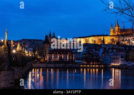 Ein atemberaubender Abendblick auf Prag, der das historische Stadtbild veranschaulicht, das vor dem Dämmerungshimmel beleuchtet wird, mit Reflexionen, die in der Moldau glitzern Stockfoto