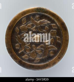 Ein dekoratives kreisförmiges Objekt mit komplexen Reliefdesigns von Vögeln und Blumenmotiven, das eine elegante Handwerkskunst zeigt, die die Kunstfertigkeit seiner Entstehung unterstreicht. Ein mittig angehobener Knopf vervollständigt die Ornamentik und verleiht dem Stück Tiefe und Textur. Islamisch, türkisch, Spiegel mit fliegenden Phönixen, 1260/1350, Bronze, 1/4 x 3/16 cm. durchm. (.64 x 8,1 cm), klassische Kunst mit modernem Touch, neu interpretiert von Artotop Stockfoto