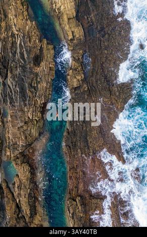 Draufsicht, aufgenommen von einer Drohne einer nicht erkennbaren Frau, die im klaren, lebhaften Wasser der natürlichen Pools am Tindaya Beach auf Fuerteventura schwimmt Stockfoto