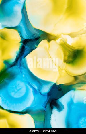 Eine lebendige Anzeige flüssiger abstrakter Tinten mit kräftigen Farbtupfern in Gelb und Blau, die sich nahtlos zu dynamischen und faszinierenden Mustern vermischen. Stockfoto
