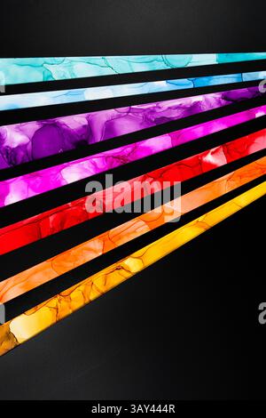 Auffällige diagonale Streifen mit leuchtenden Farben, darunter Blau, Lila, Rosa, Rot und Gelb, bilden einen scharfen Kontrast zu einem schwarzen Hintergrund und erzeugen so einen Stockfoto