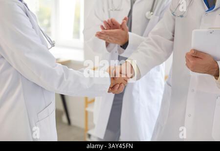 Zwei Ärzte in weißen Mänteln schütteln in der Klinik die Hände, feiern Teamarbeit und Behandlungserfolg. Stockfoto