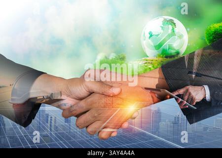 Zwei Menschen, die nach dem Abschluss des Abkommens über erneuerbare Energien die Hände gegen das Solarpanel schütteln. Doppelt belichtete Geschäftsleute Stockfoto