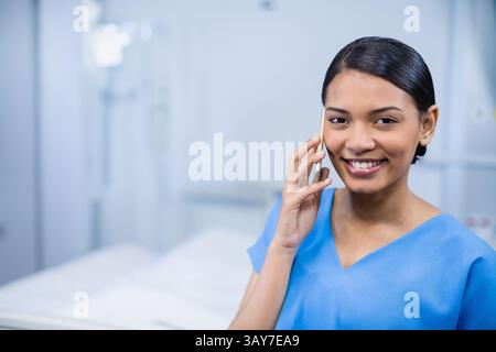 Krankenschwester steht im Krankenhauszimmer neben Bett mit Infusionsständer, spricht über Smartphone, Kopierraum Stockfoto