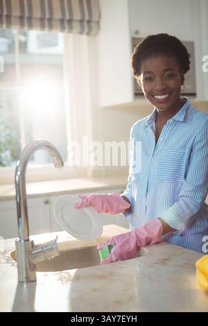 Afroamerikanerin, die Geschirr am Spülbecken mit grünem Schwamm in rosa Handschuhen wäscht, Kopierraum Stockfoto