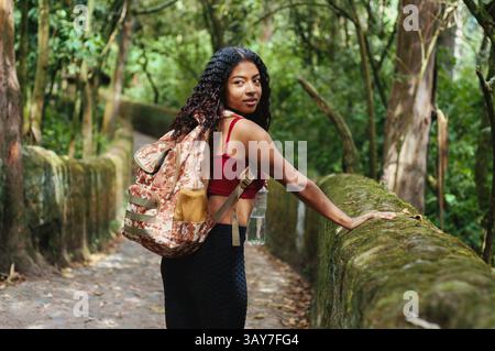 Eine junge Frau erkundet freudig einen üppigen Pfad, der den Geist des Abenteuers und die Schönheit der Natur umfasst Stockfoto