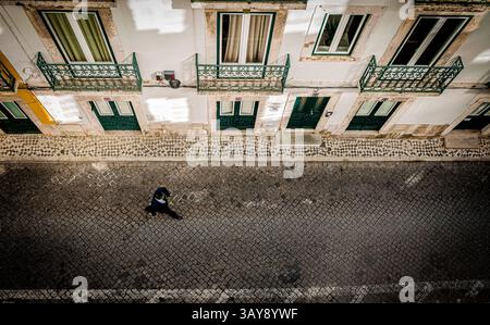 Ich schaue auf einen Mann, der in Lissabon in einer Kopfsteinpflasterstraße läuft Stockfoto