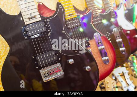 Eine Reihe verschiedener E-Gitarren hängen in der Nähe des Musikgeschäfts Stockfoto