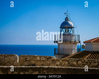 Eine Nahaufnahme des weißen und silbernen Leuchtturms von Peniscola (Faro de Peniscola), der deutlich vor dem klaren blauen Himmel und dem tiefblauen Mittelmeer steht Stockfoto