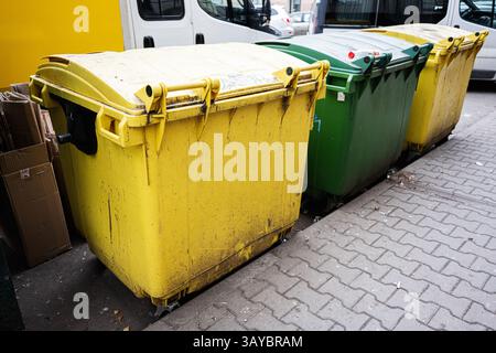 Recyclingbehälter in verschiedenen Farben an einer gepflasterten Straßenecke Stockfoto