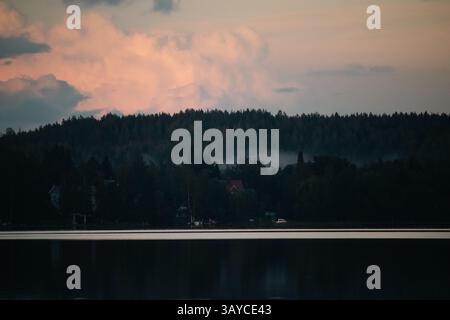 Ein bedeckter Spätsommer mit einer Hütte am Horizont über einem ruhigen See. Stockfoto