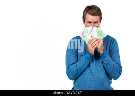 Mann hält Euro-Banknoten im Studio über Gesicht, zeigt spielerischen Ausdruck, Kopierraum Stockfoto