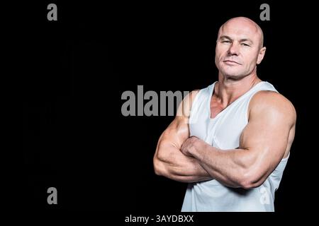 Mann mittleren Alters, der mit gekreuzten Armen im Studio steht, mit weißem Tanktop, Kopierraum Stockfoto