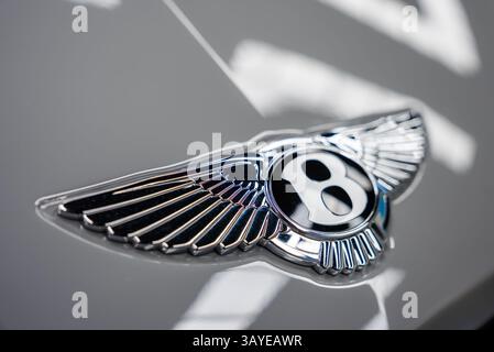 Nahaufnahme des Bentley-Logos mit silbernen Flügeln auf reflektierender Oberfläche Stockfoto