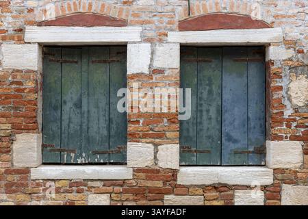 Alte Holzläden an der Ziegelmauer Stockfoto