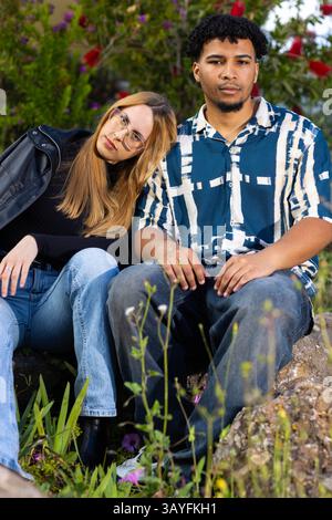 Stilvolles junges Paar, das zusammen in einem Garten sitzt und einen friedlichen Moment in der Natur genießt Stockfoto