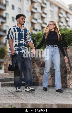 Ein junges Paar lächelt und läuft zusammen in der Stadt Stockfoto