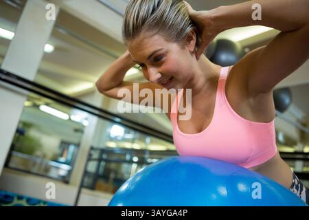 Frau, die ab-Workout auf blauem Stabilitätsball im Fitnessstudio mit Spiegelwand, Kopierraum macht Stockfoto