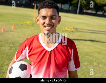 Männlicher Fußballspieler, der auf dem Outdoor-Trainingsfeld Übungen macht und den Ball mit Kegeln und Hürden hält Stockfoto