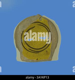 Ein Fragment von Töpferwaren mit einer leuchtend gelben Glasur, verziert mit einem kreisförmigen Design, das in dunklen Linien umrandet ist, vor einem kontrastierenden Hintergrund. Das Stück zeigt Zeichen des Alters und der Handwerkskunst, was seine historische Bedeutung widerspiegelt. Fragment of a Bowl, 13./14. Jahrhundert, Byzantinisch, Griechenland, Thessaloniki, Istanbul, Keramik, 2,2 x 7 x 6 cm (7/8 x 2 3/4 x 2 3/8 Zoll) Klassische Kunst mit modernem Touch, neu interpretiert von Artotop Stockfoto